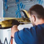 Car mechanic working to remove dent in workshop.